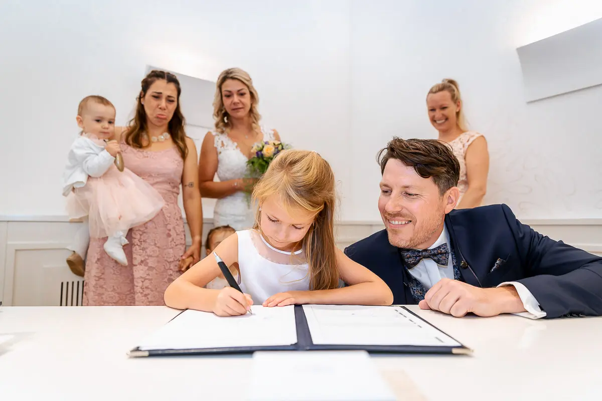 Ehepaar und Kind unterschreiben die Trauurkunde